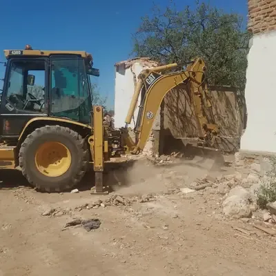 Retroexcavadora derribando un muro